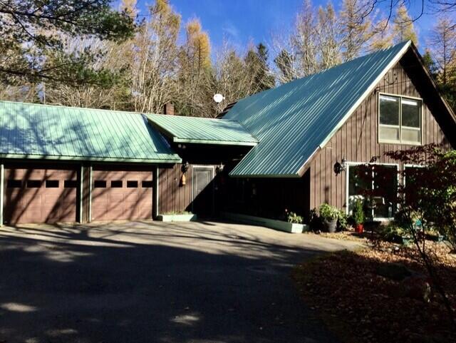 exterior space featuring a chimney, metal roof, and driveway