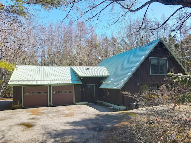 exterior space featuring an attached garage, metal roof, and aphalt driveway