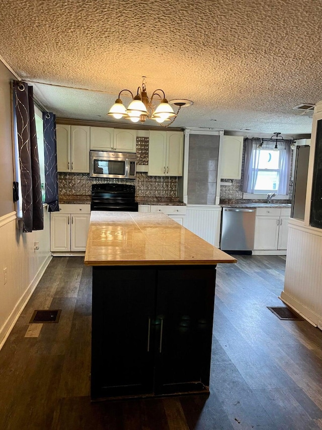 642 Main St, Old Town, ME 04468 - kitchen featuring dark wood finished floors, wainscoting, visible vents, and appliances with stainless steel finishes