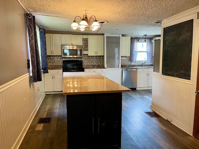 642 Main St, Old Town, ME 04468 - kitchen featuring dark wood finished floors, visible vents, a wainscoted wall, and appliances with stainless steel finishes