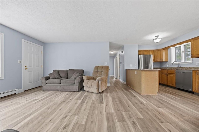 living area featuring light wood finished floors, a textured ceiling, and baseboards