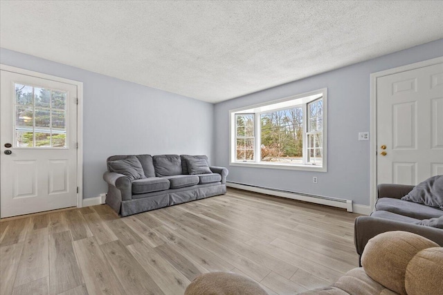 living room featuring a baseboard radiator, baseboards, wood finished floors, and a textured ceiling