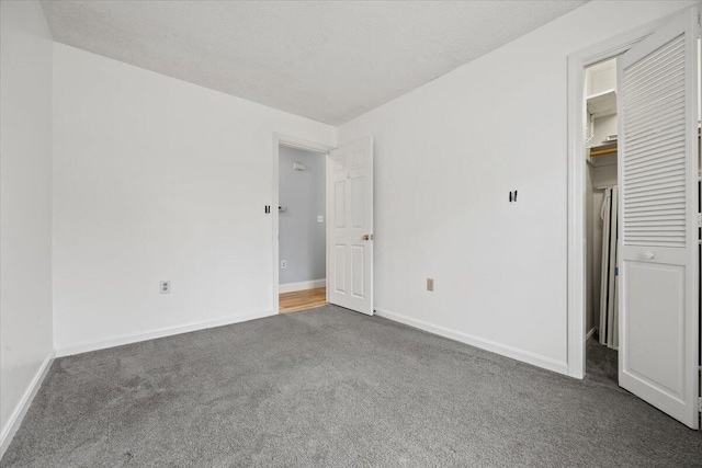 unfurnished bedroom with a closet, baseboards, a spacious closet, and carpet