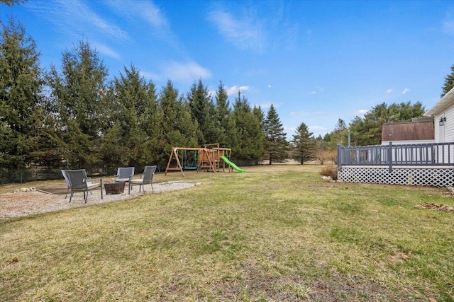 view of yard with a playground, a fire pit, and a wooden deck