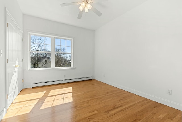 spare room featuring baseboards, a baseboard heating unit, and wood finished floors