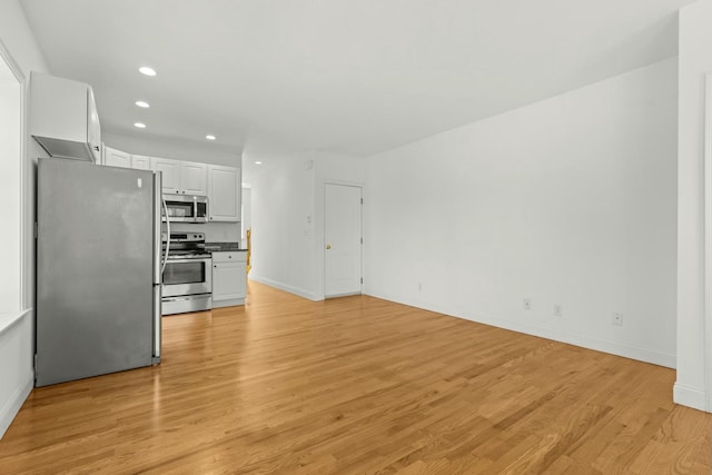 unfurnished living room with light wood-type flooring, baseboards, and recessed lighting