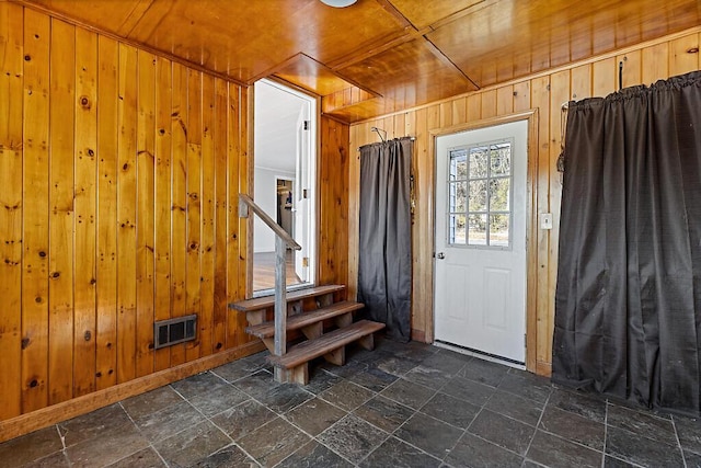 interior space with wooden ceiling, stone tile floors, wooden walls, and visible vents