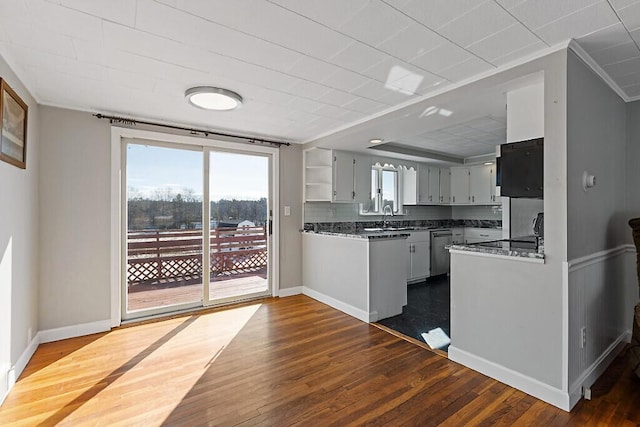 kitchen featuring dark wood-type flooring, stainless steel dishwasher, a sink, and open shelves