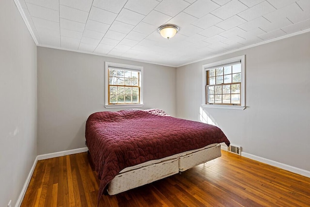 bedroom with visible vents, multiple windows, baseboards, and wood finished floors