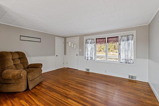 sitting room featuring visible vents, wood finished floors, and wainscoting