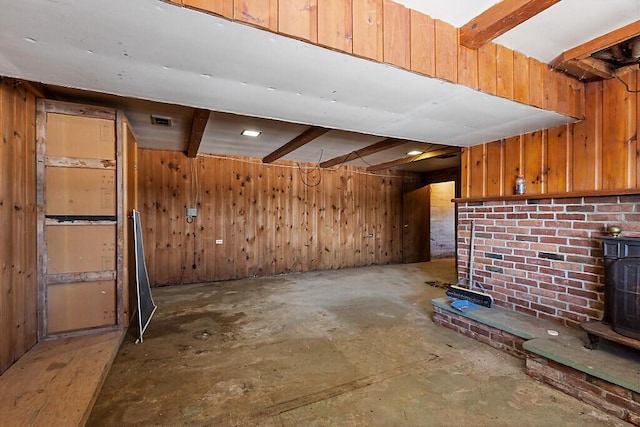 below grade area featuring wooden walls, visible vents, and a wood stove