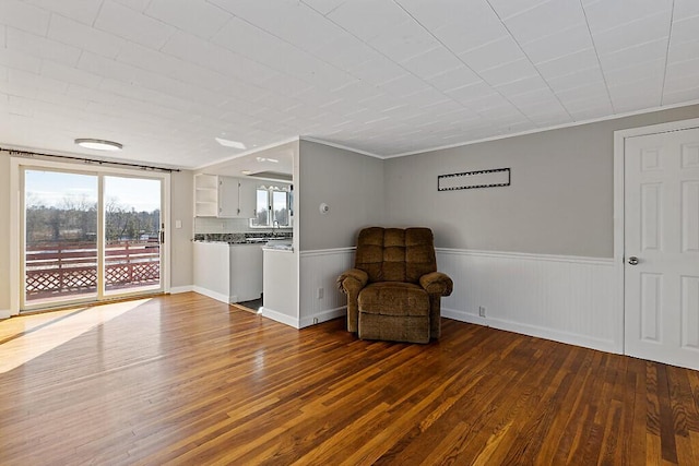 living area featuring wainscoting, ornamental molding, and dark wood-style floors