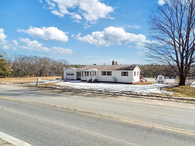 view of front facade featuring a detached garage, driveway, and a chimney