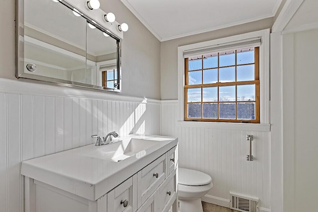 bathroom featuring visible vents, toilet, crown molding, wainscoting, and vanity