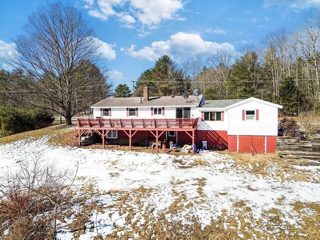 snow covered rear of property featuring a deck and a chimney