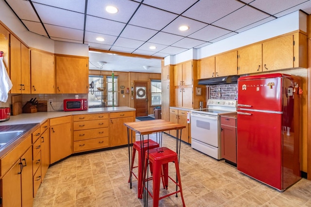 kitchen with backsplash, under cabinet range hood, light countertops, and white appliances