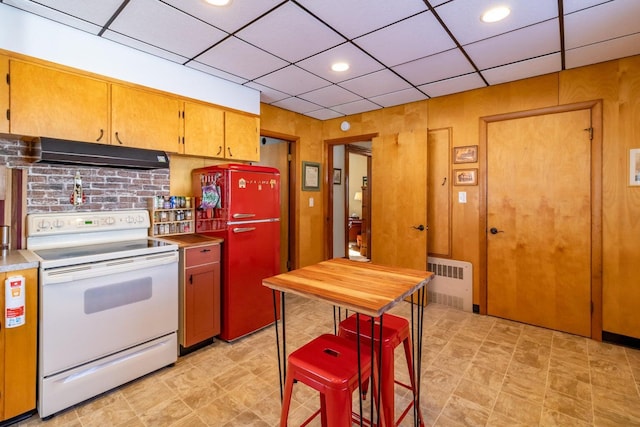 kitchen with a paneled ceiling, freestanding refrigerator, exhaust hood, white range with electric cooktop, and radiator heating unit