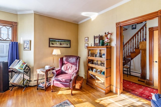 living area featuring crown molding, stairway, a baseboard heating unit, wood-type flooring, and baseboards