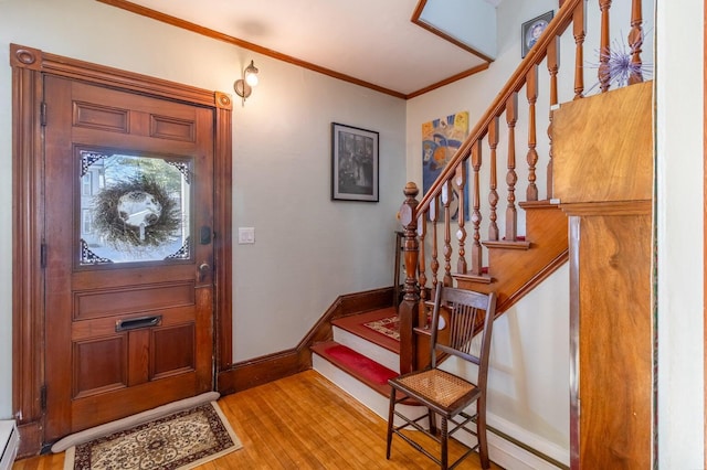 foyer entrance with crown molding, light wood-style flooring, baseboard heating, stairs, and baseboards