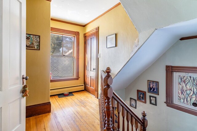 entrance foyer featuring baseboard heating, light wood-style floors, crown molding, and baseboards