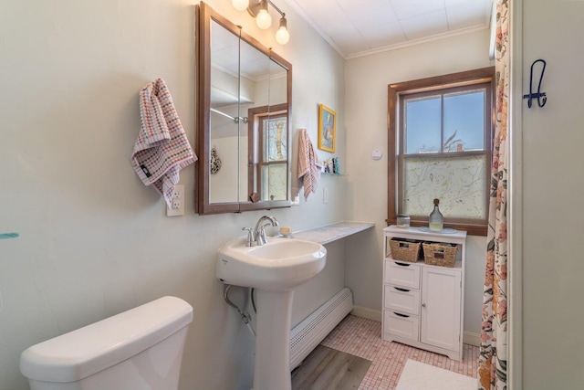 full bath with ornamental molding, toilet, a baseboard heating unit, and baseboards
