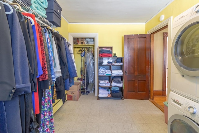 laundry area featuring stacked washing maching and dryer, laundry area, crown molding, and tile patterned floors