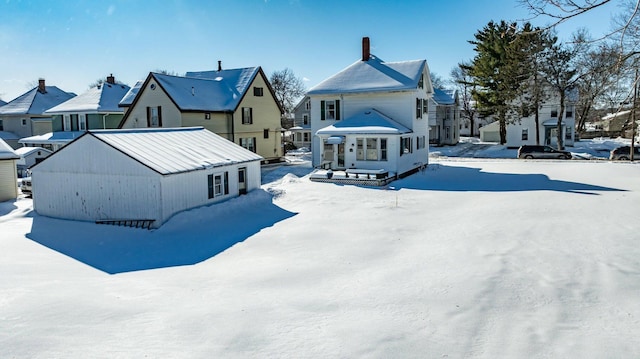 snow covered house with a chimney and a residential view