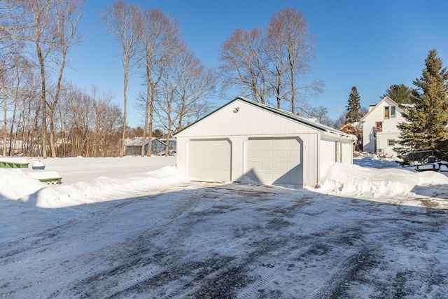 snow covered garage with a detached garage