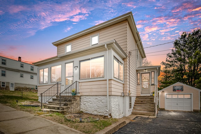 traditional-style house with an outdoor structure, aphalt driveway, entry steps, and a garage