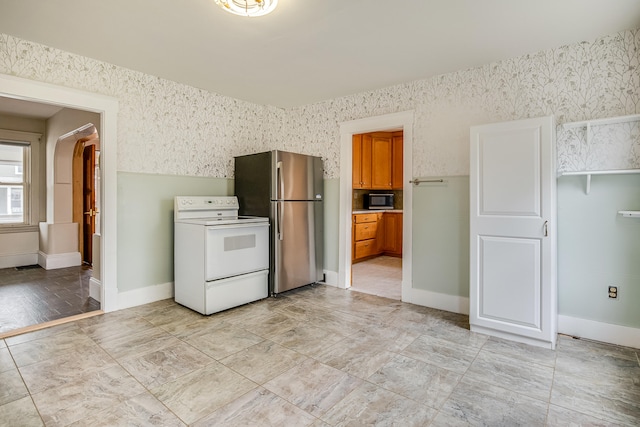 interior space featuring white electric range oven, freestanding refrigerator, wallpapered walls, brown cabinetry, and black microwave