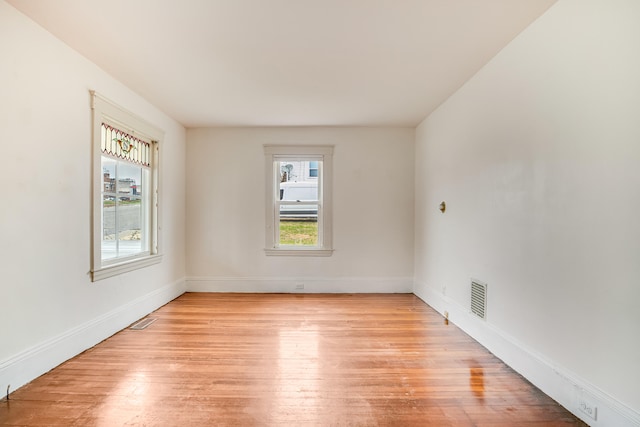 unfurnished room with light wood finished floors, baseboards, and visible vents