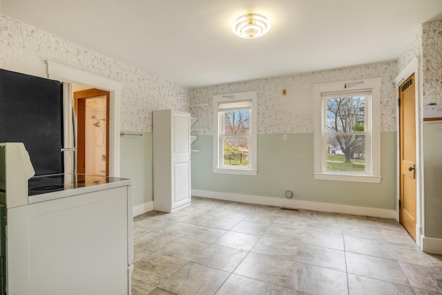 interior space featuring wallpapered walls, plenty of natural light, and baseboards