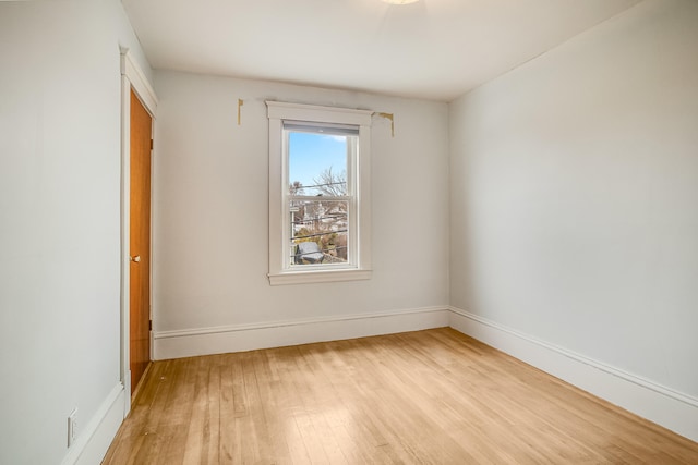 empty room with baseboards and light wood-type flooring