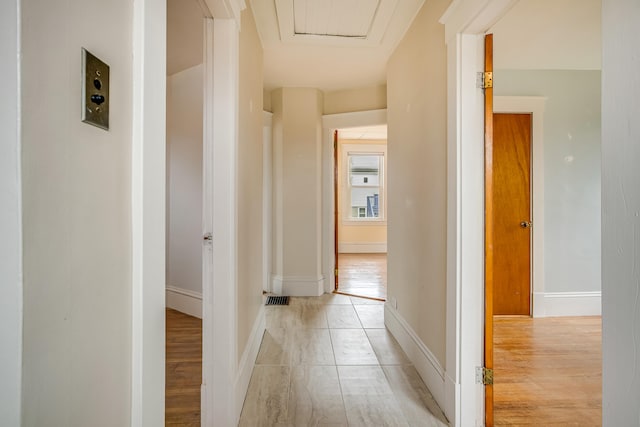 corridor featuring light wood-style flooring, visible vents, and baseboards