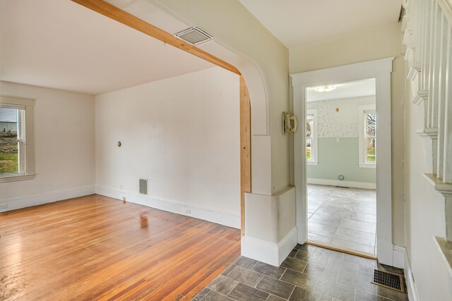 unfurnished room featuring arched walkways, visible vents, and baseboards