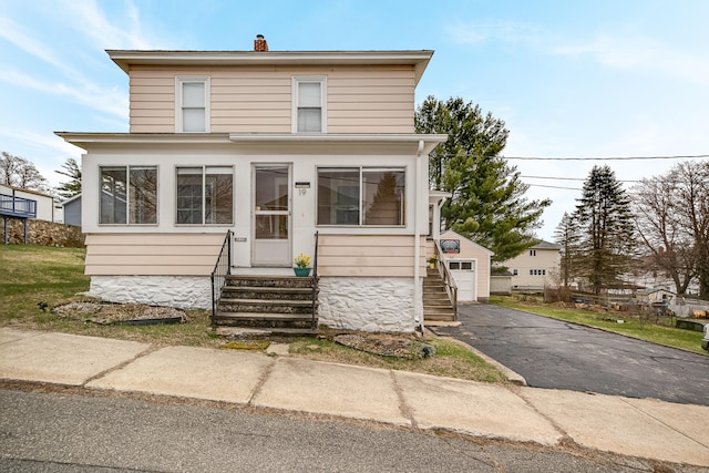 view of front of property with a detached garage, a chimney, driveway, an outbuilding, and entry steps