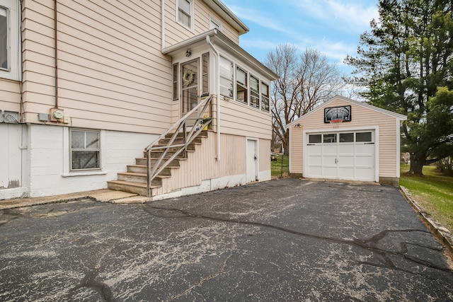 view of side of home with a detached garage, an outbuilding, stairs, and driveway