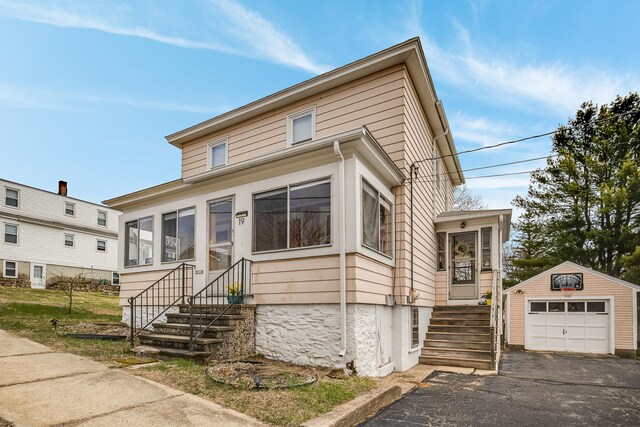 traditional home with a detached garage, an outbuilding, and aphalt driveway