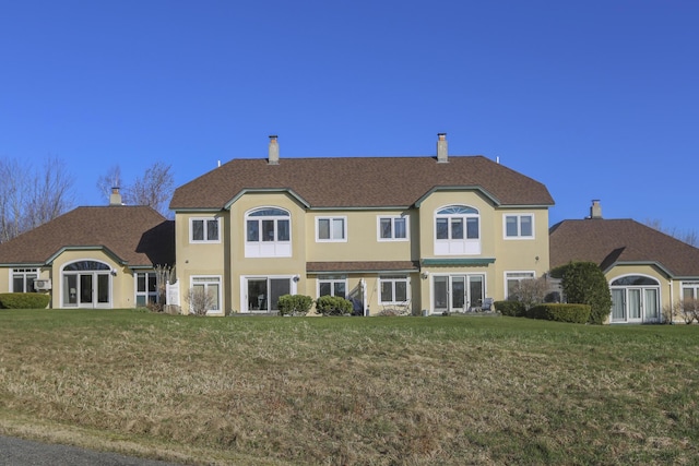 rear view of property featuring stucco siding, a chimney, a yard, and french doors