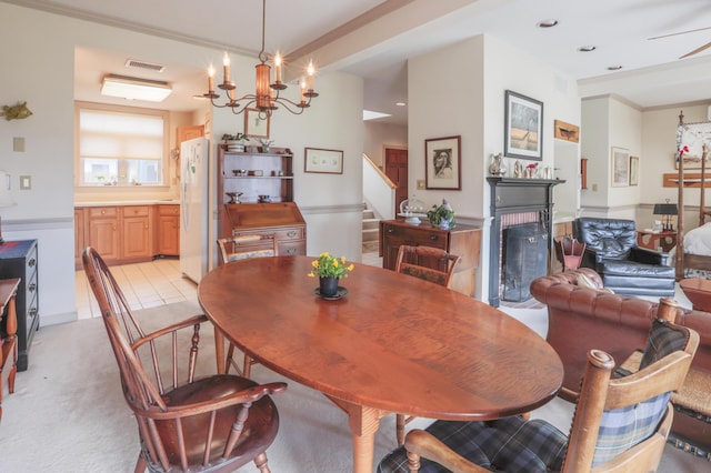 dining room with stairway, a chandelier, a fireplace, visible vents, and light colored carpet