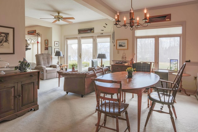 dining space with ornamental molding, light colored carpet, and ceiling fan with notable chandelier