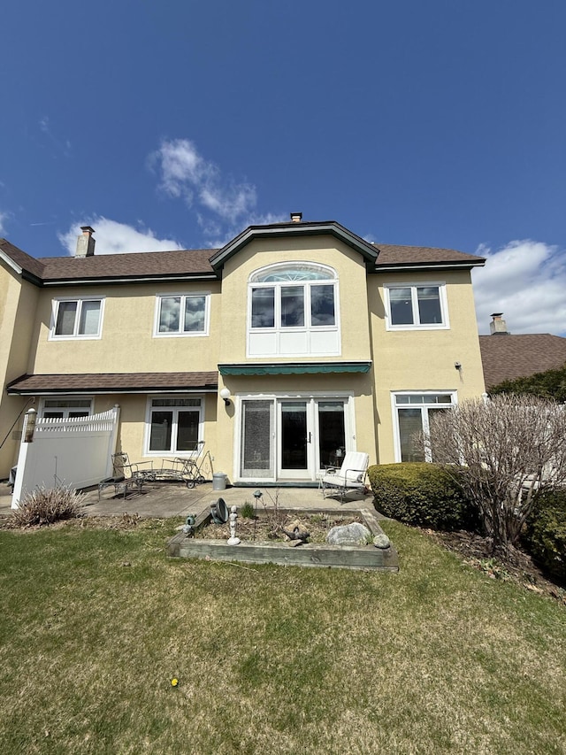 rear view of house featuring a lawn, stucco siding, and a patio area