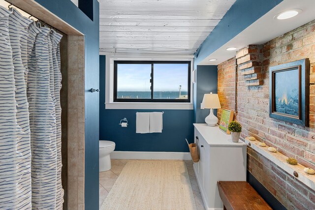 21 Atlantic St, Rockland, ME 04841 - bathroom featuring baseboards, curtained shower, brick wall, toilet, and tile patterned flooring