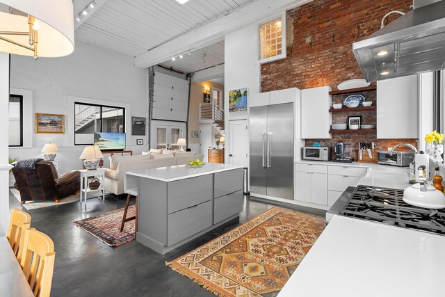 21 Atlantic St, Rockland, ME 04841 - kitchen featuring open shelves, a high ceiling, stainless steel built in fridge, white microwave, and rail lighting