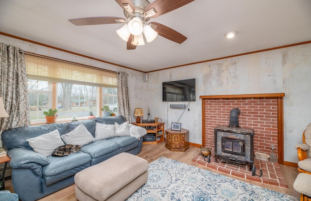481 Washington Rd, Jefferson, ME 04348 - living room featuring a wood stove, a ceiling fan, ornamental molding, wood finished floors, and a baseboard radiator