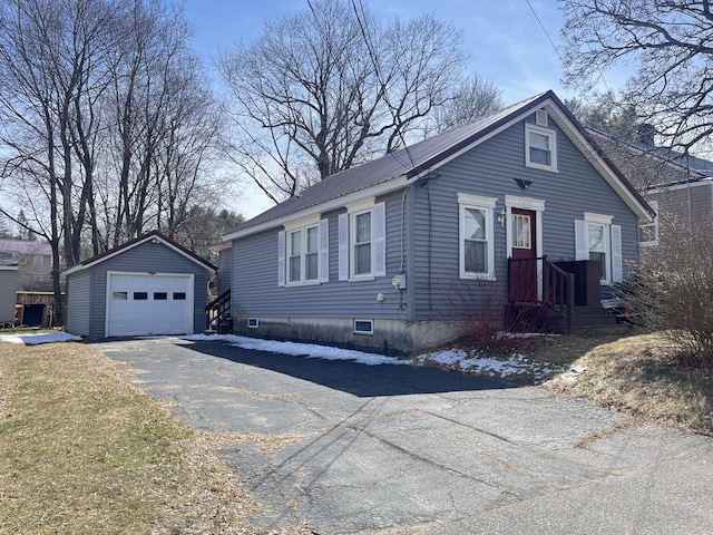 view of front of house with a garage, aphalt driveway, metal roof, and an outdoor structure