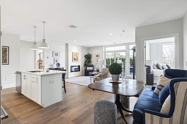 interior space with white cabinets, a sink, open floor plan, stainless steel dishwasher, and visible vents