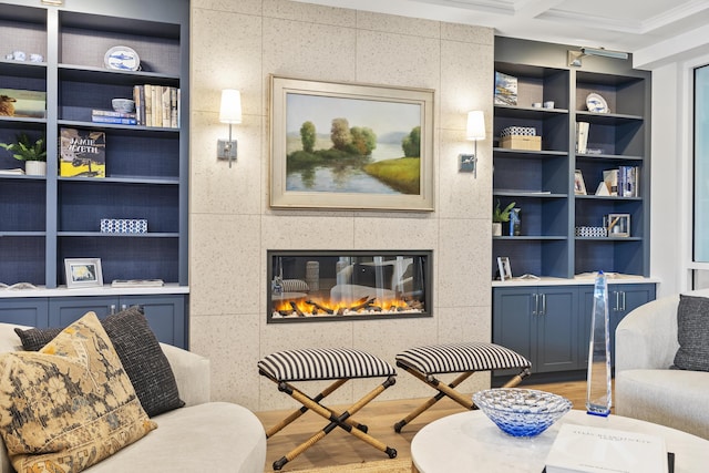 living area featuring crown molding, built in features, wood finished floors, and a tile fireplace