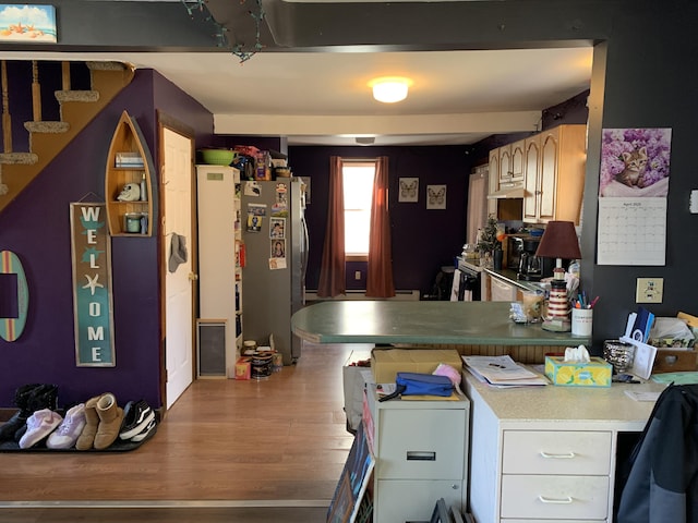 kitchen with a peninsula, wood finished floors, freestanding refrigerator, and under cabinet range hood