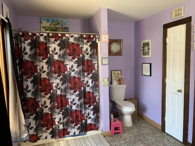 full bath with toilet, curtained shower, and baseboards